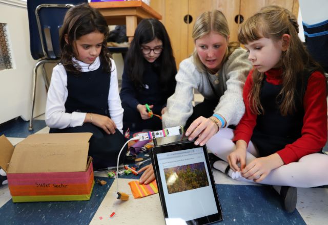 lower school students and reacher using ipad and robotics components