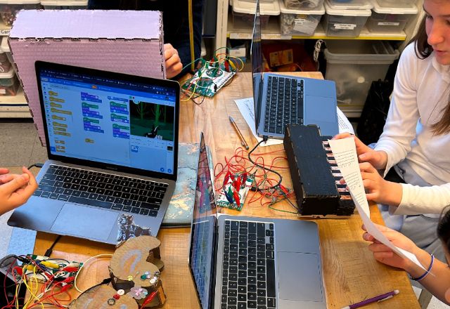 upper school students using laptops and robotics components