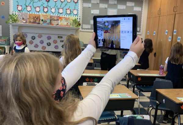 lower school student using augmented reality camera program on an iPad