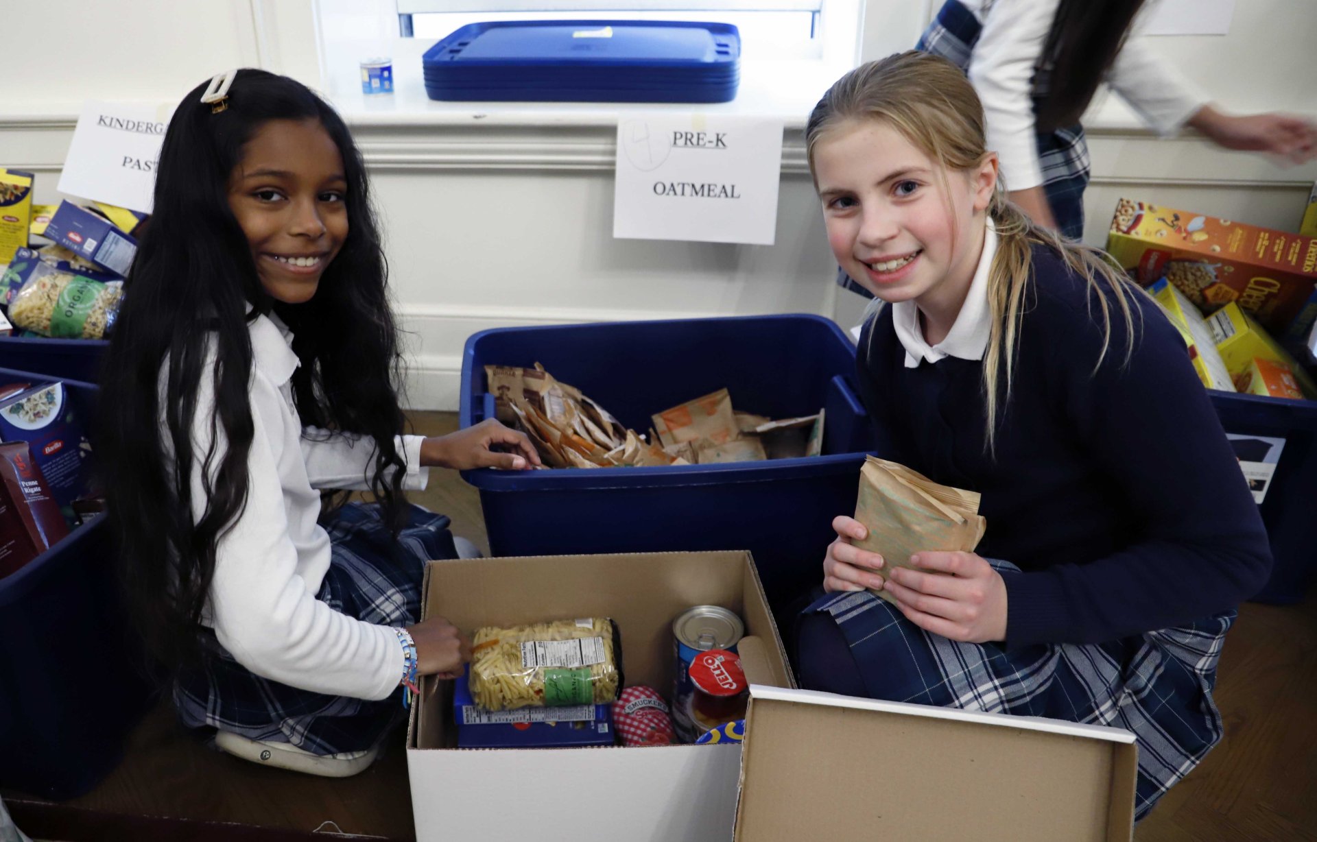 two students putting together food packages for food drive
