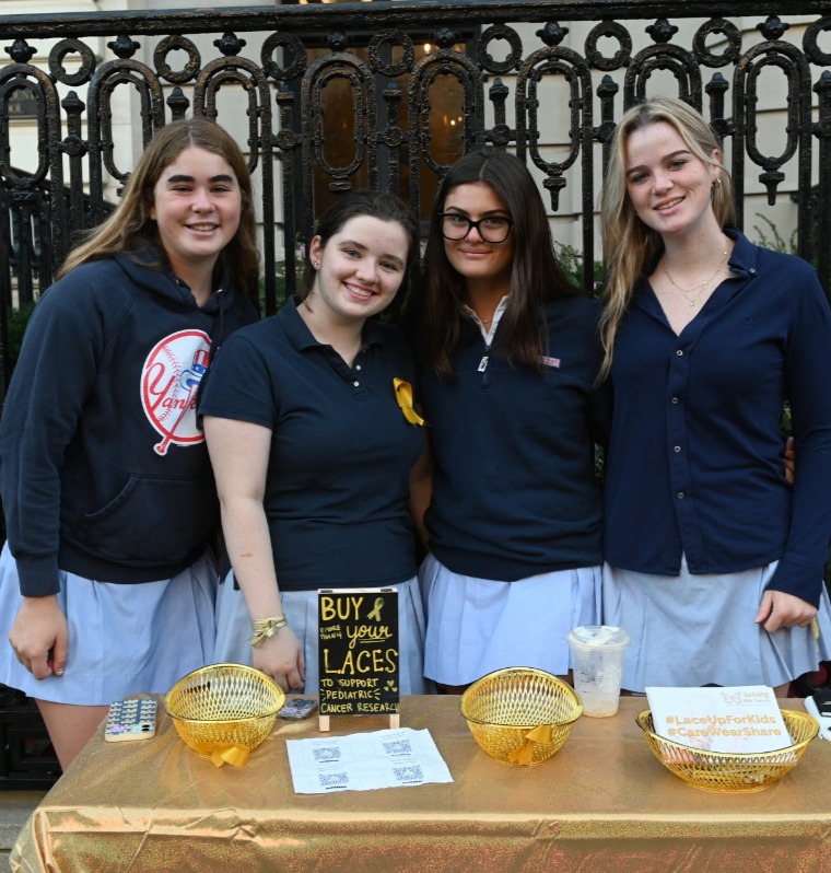 four students at community event table