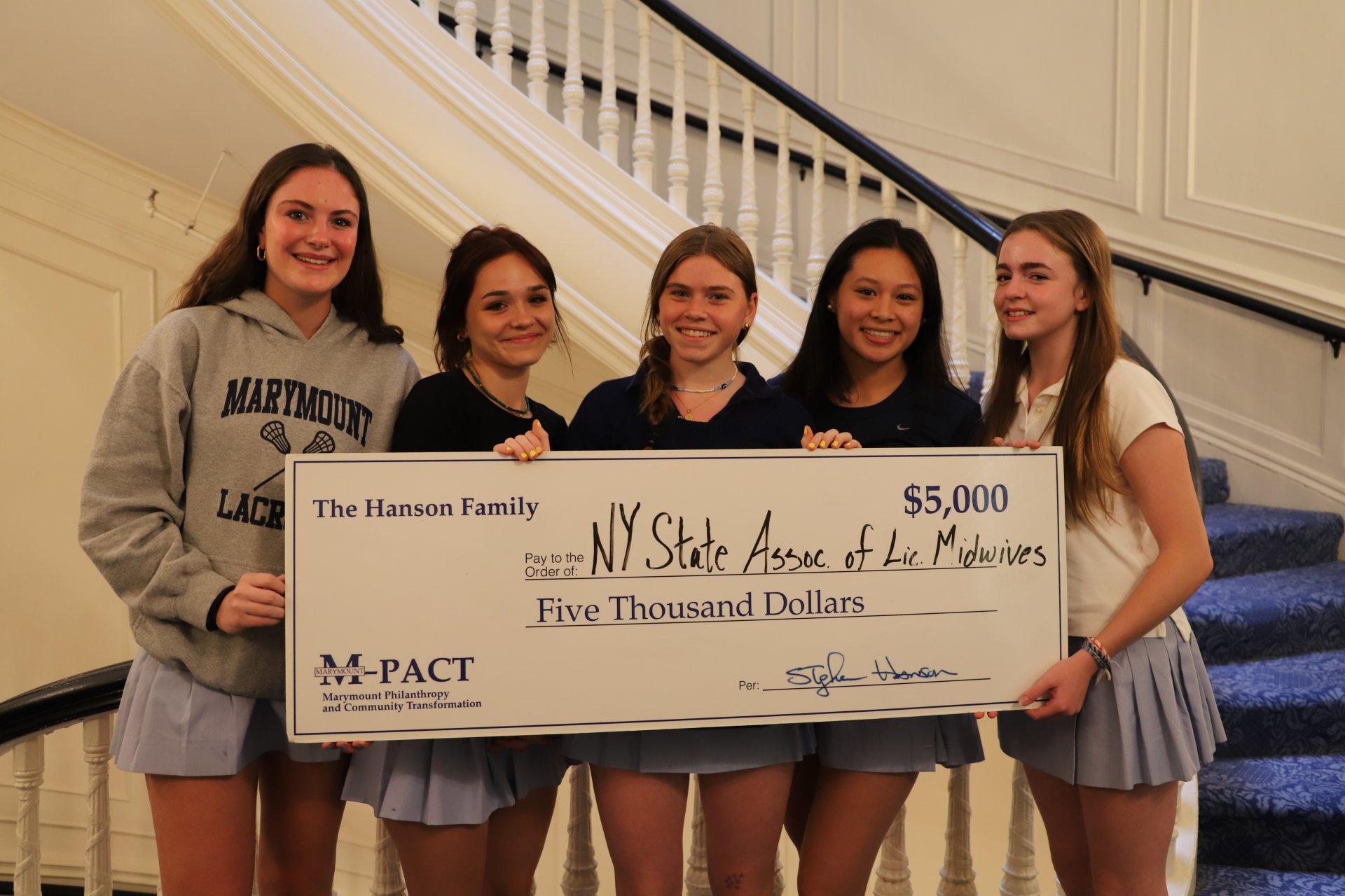 four students holding a donation check from MPACT