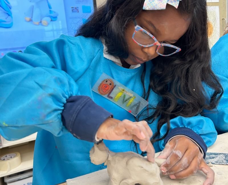 lower school student sculpting clay