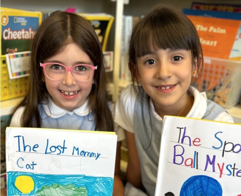 two lower school students holding handmade books