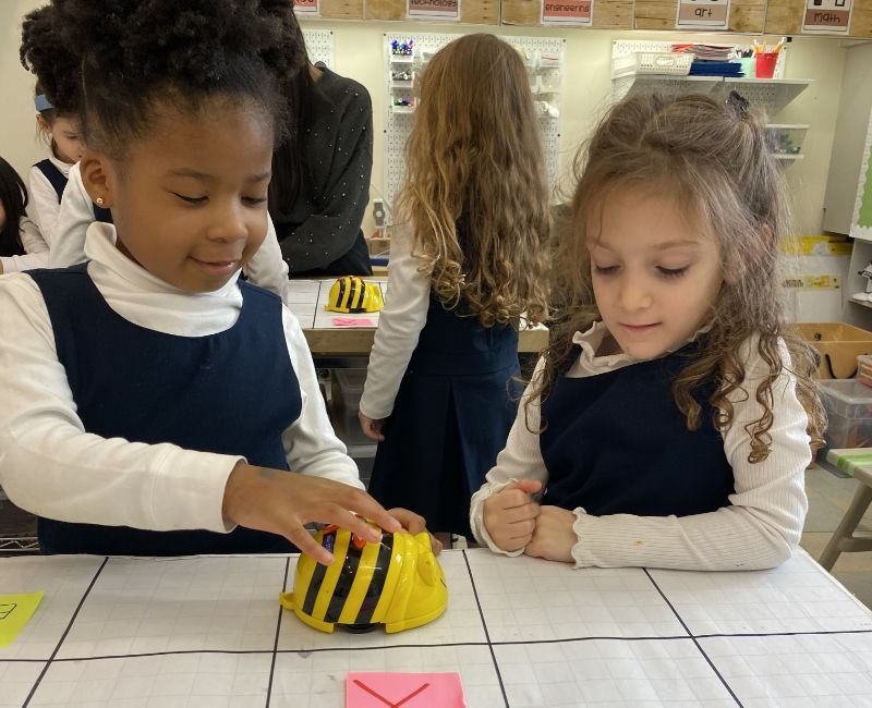two lower school students learning with bumble bee robot toy