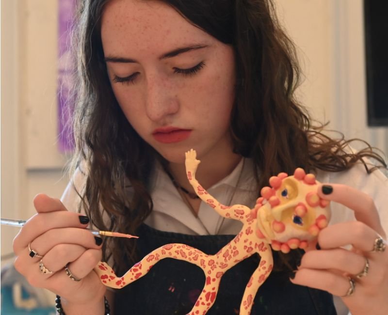 upper school student painting a sculpture