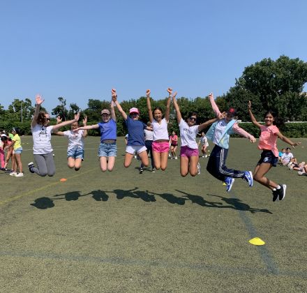 group of students jumping on outdoor sport field