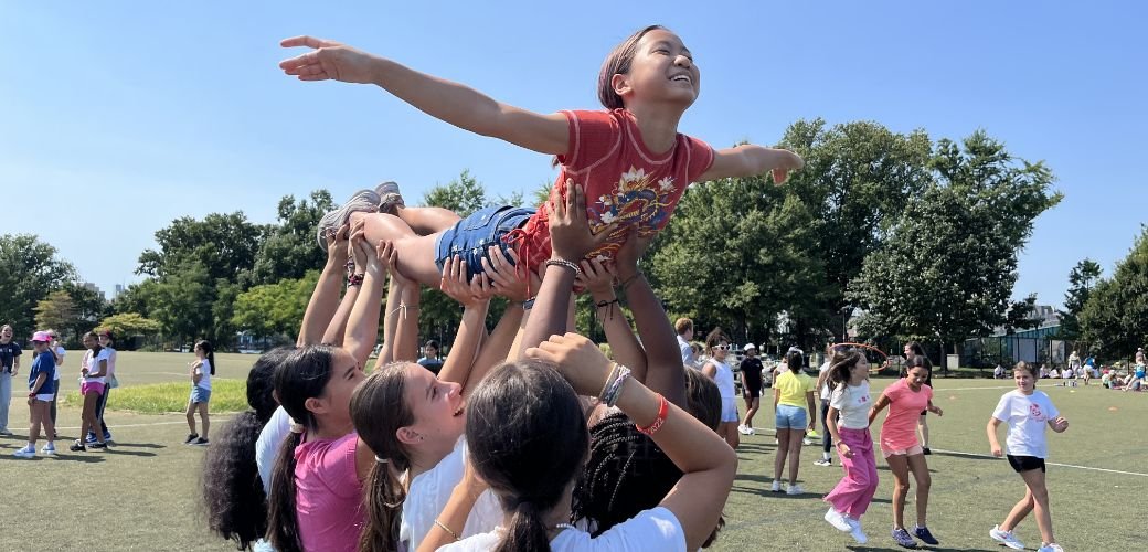 group of students holding up a single student outdoors
