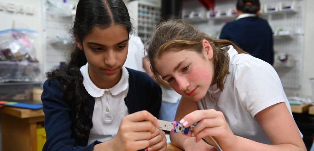 two upper school students working with robotics components